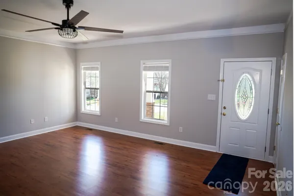 a view of an empty room with window and wooden floor