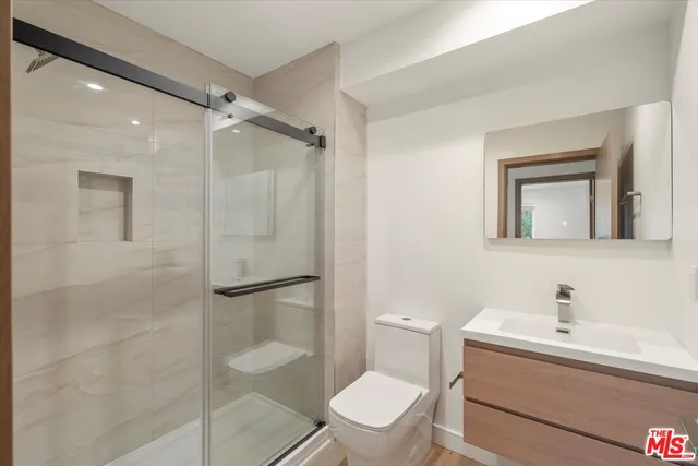 a bathroom with a toilet sink vanity and shower