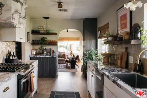 a kitchen with stainless steel appliances granite countertop a stove a sink dishwasher and cabinets with wooden floor