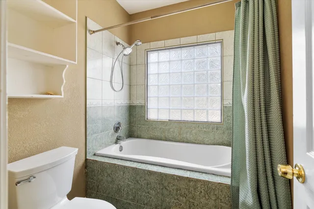 a bathroom with a granite countertop bathtub shower and toilet
