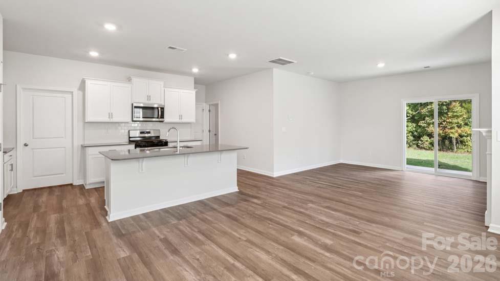170 Old Home Road Statesville, NC 28677 - Photo 17 of 40 a kitchen with stainless steel appliances kitchen island granite countertop a stove a refrigerator a sink a microwave and white cabinets with wooden floor