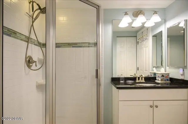 a bathroom with a granite countertop sink a mirror and a shower