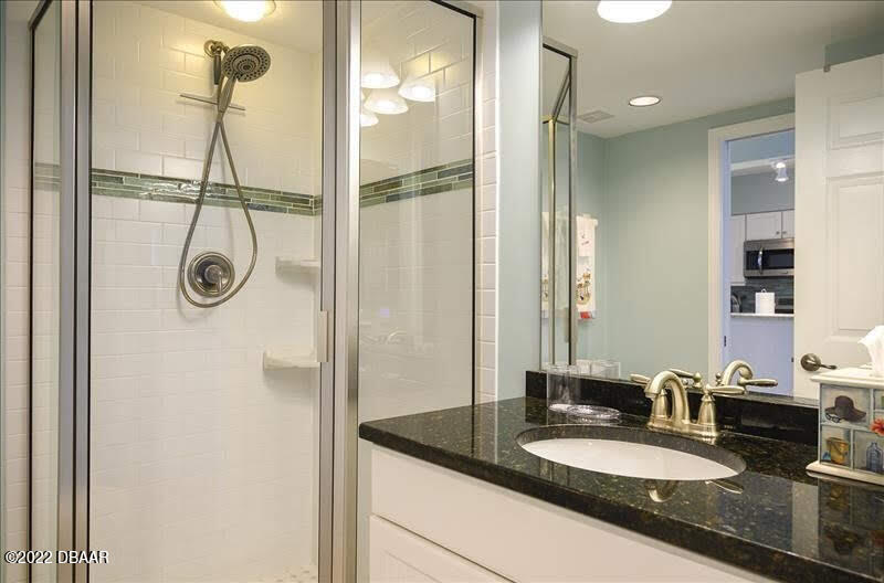 4555 South Atlantic Avenue, Unit 4207 Ponce Inlet, FL 32127 - Photo 26 of 33 a bathroom with a granite countertop sink a mirror and a shower