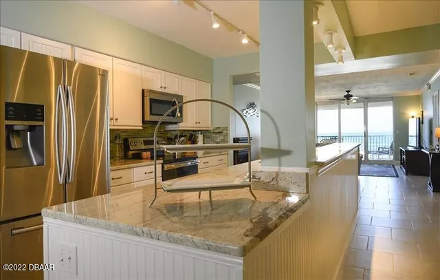 a kitchen with stainless steel appliances granite countertop a refrigerator a stove and white cabinets with wooden floor