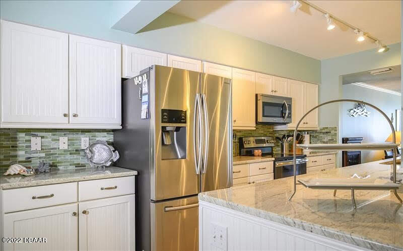 4555 South Atlantic Avenue, Unit 4207 Ponce Inlet, FL 32127 - Photo 8 of 33 a kitchen with stainless steel appliances granite countertop a refrigerator a stove and a sink with cabinets