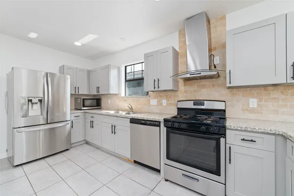 a kitchen with granite countertop white cabinets and stainless steel appliances
