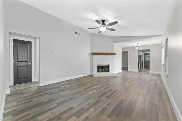 a view of an empty room with wooden floor and a fireplace