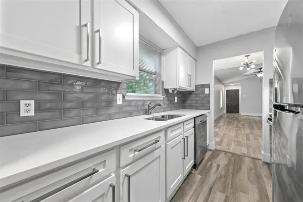 a kitchen with a sink dishwasher a stove and a refrigerator with wooden floor