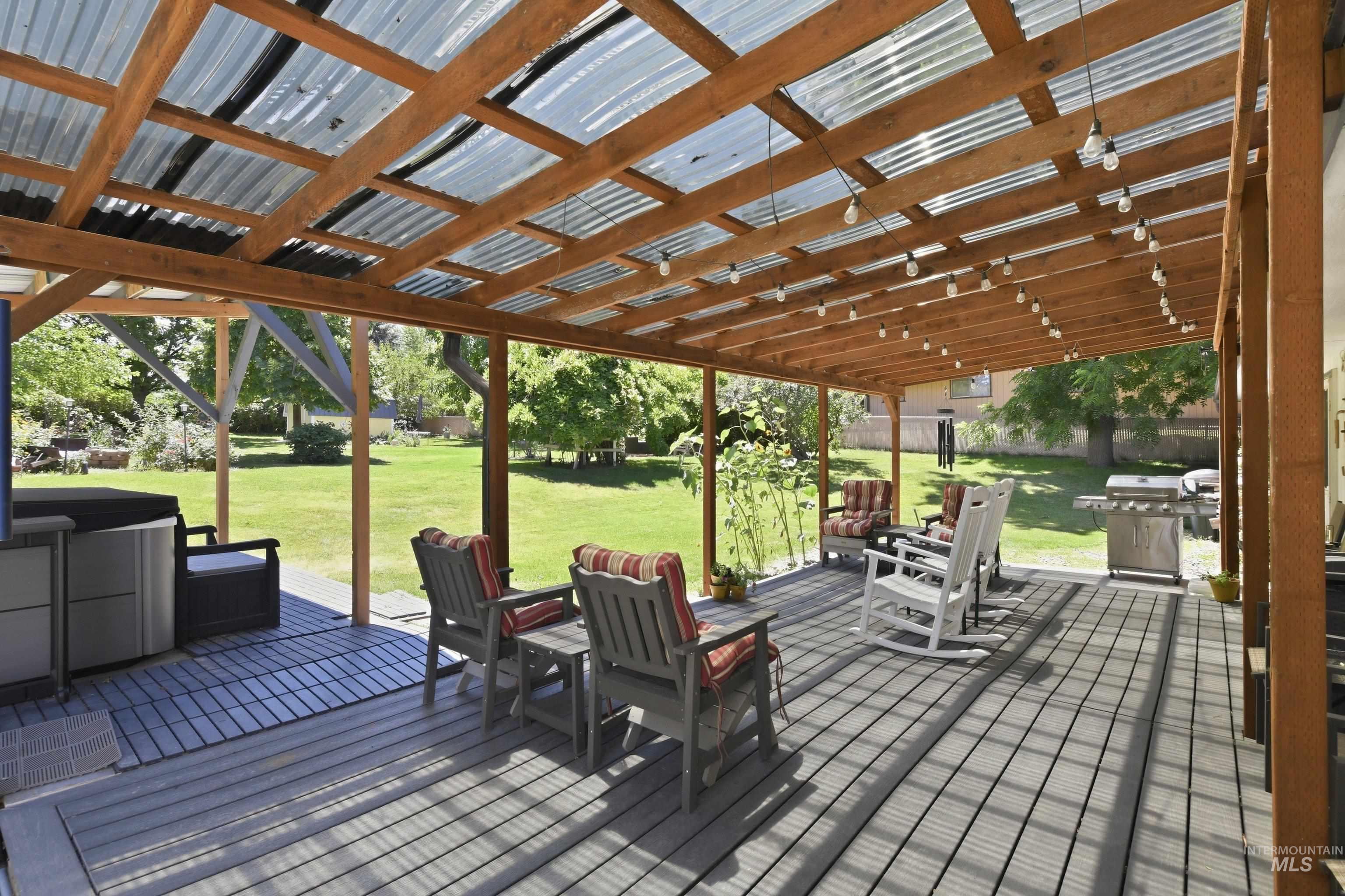15095 David Street Caldwell, ID 83607 - Photo 28 of 39 Spacious covered patio featuring a corrugated translucent roof, exposed wood beams, and string lighting