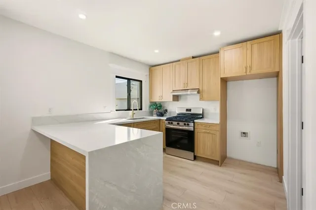 a kitchen with stainless steel appliances a stove a refrigerator a sink a oven with white cabinets