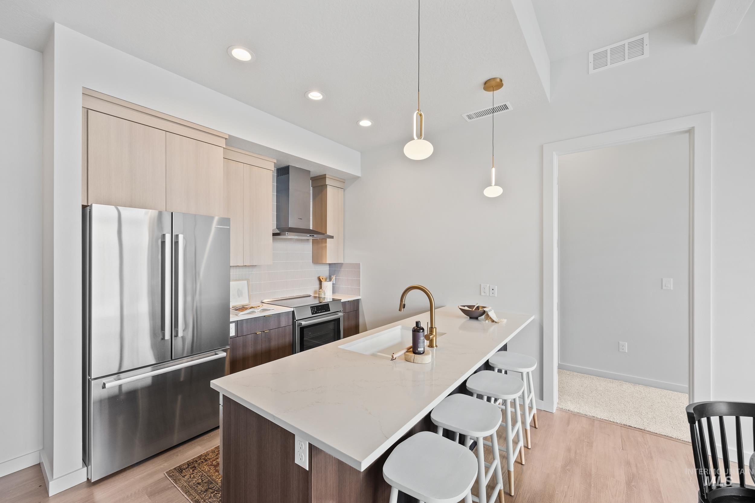 4340 East Haystack Street, Unit 305 Boise, ID 83716 - Photo 5 of 50 Kitchen featuring modern cabinets, appliances with stainless steel finishes, light stone counters, decorative backsplash, and a kitchen bar