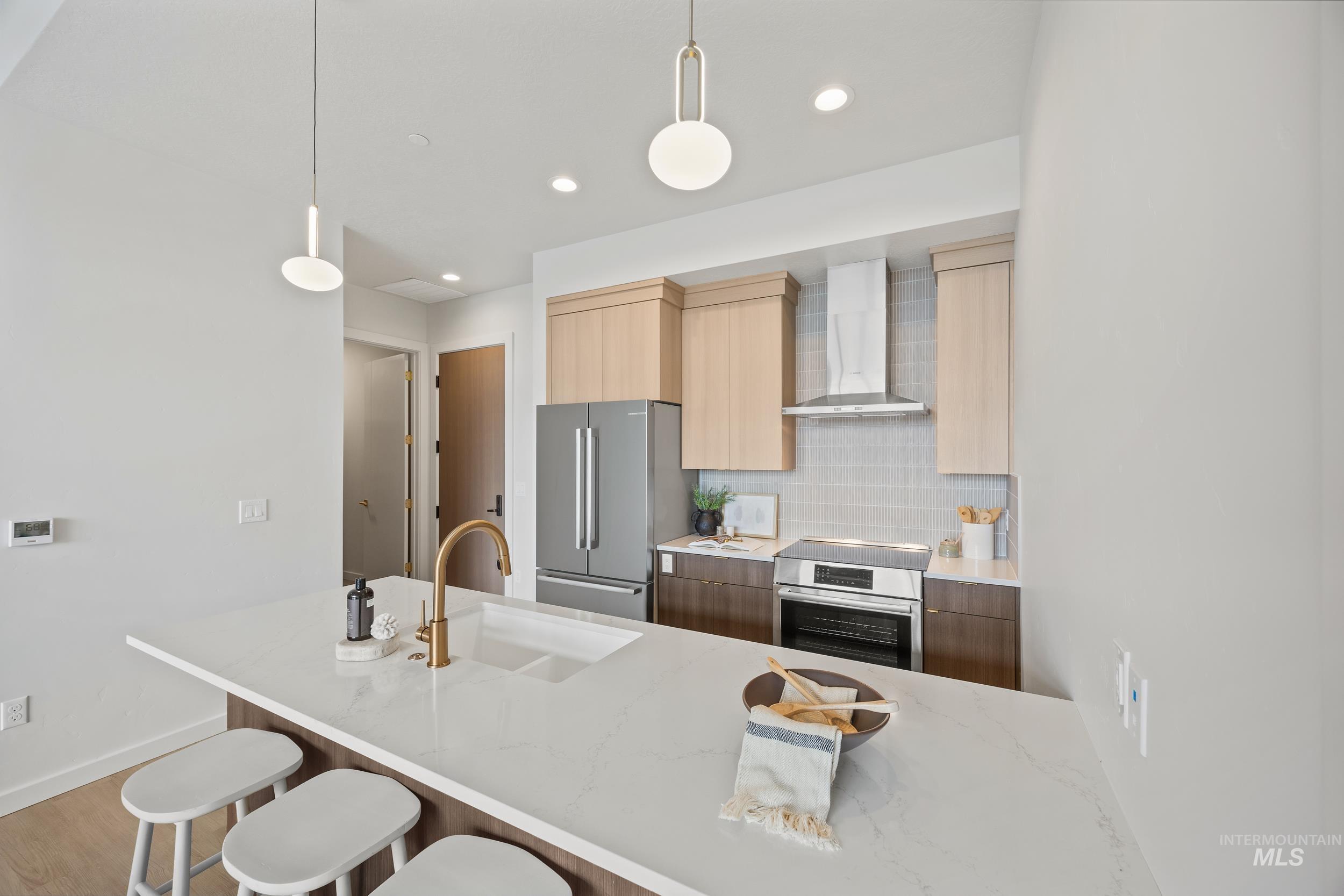 4340 East Haystack Street, Unit 305 Boise, ID 83716 - Photo 6 of 50 Kitchen with backsplash, pendant lighting, light stone counters, modern cabinets, and wall chimney exhaust hood