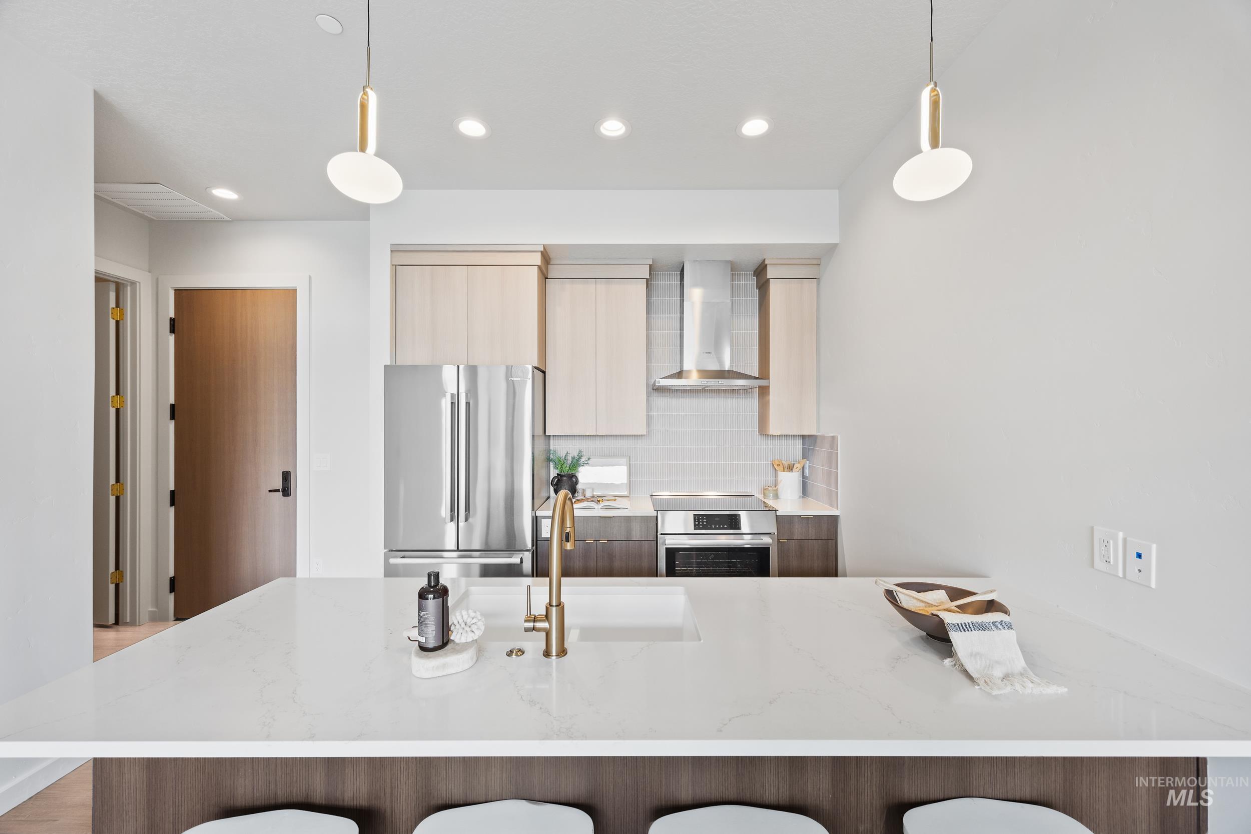 4340 East Haystack Street, Unit 305 Boise, ID 83716 - Photo 7 of 50 Kitchen with decorative backsplash, light stone countertops, modern cabinets, appliances with stainless steel finishes, and a peninsula