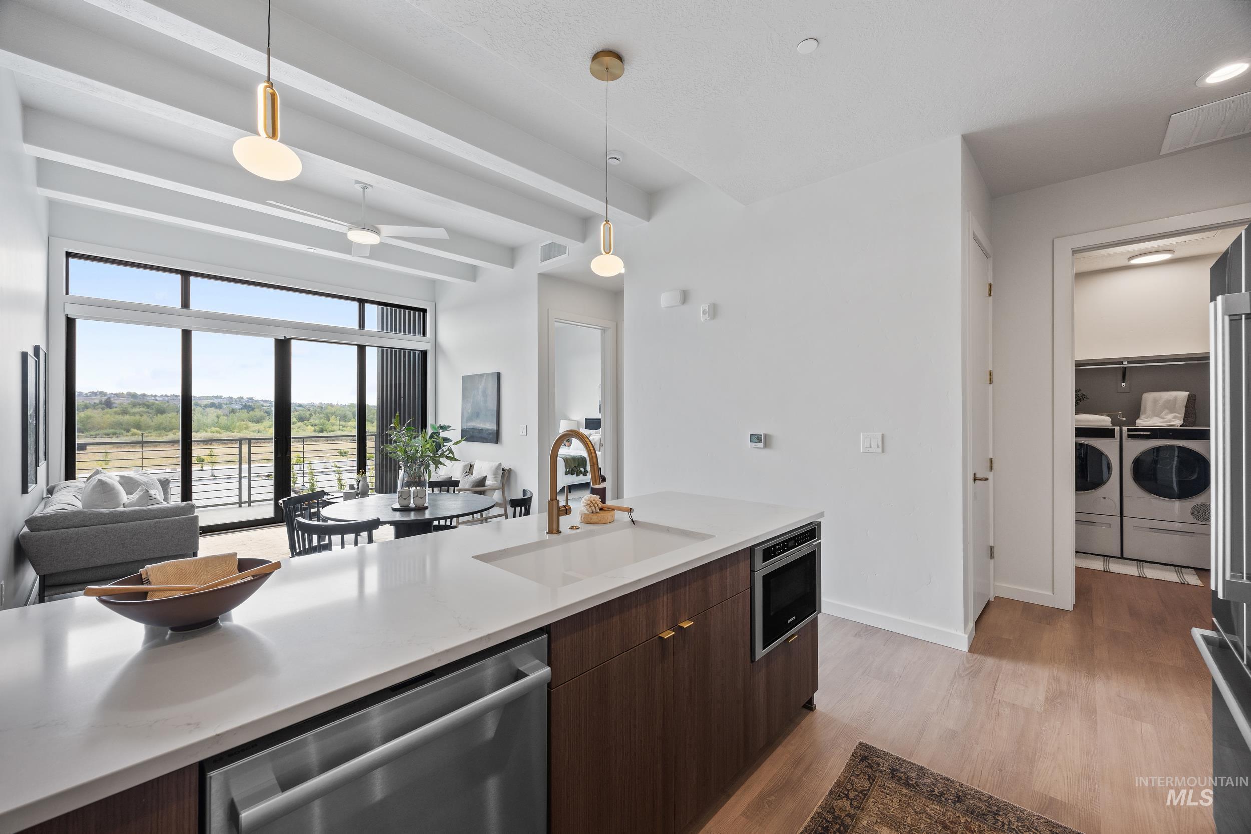 4340 East Haystack Street, Unit 305 Boise, ID 83716 - Photo 50 of 50 Kitchen with stainless steel appliances, open floor plan, dark brown cabinets, pendant lighting, and light wood finished floors
