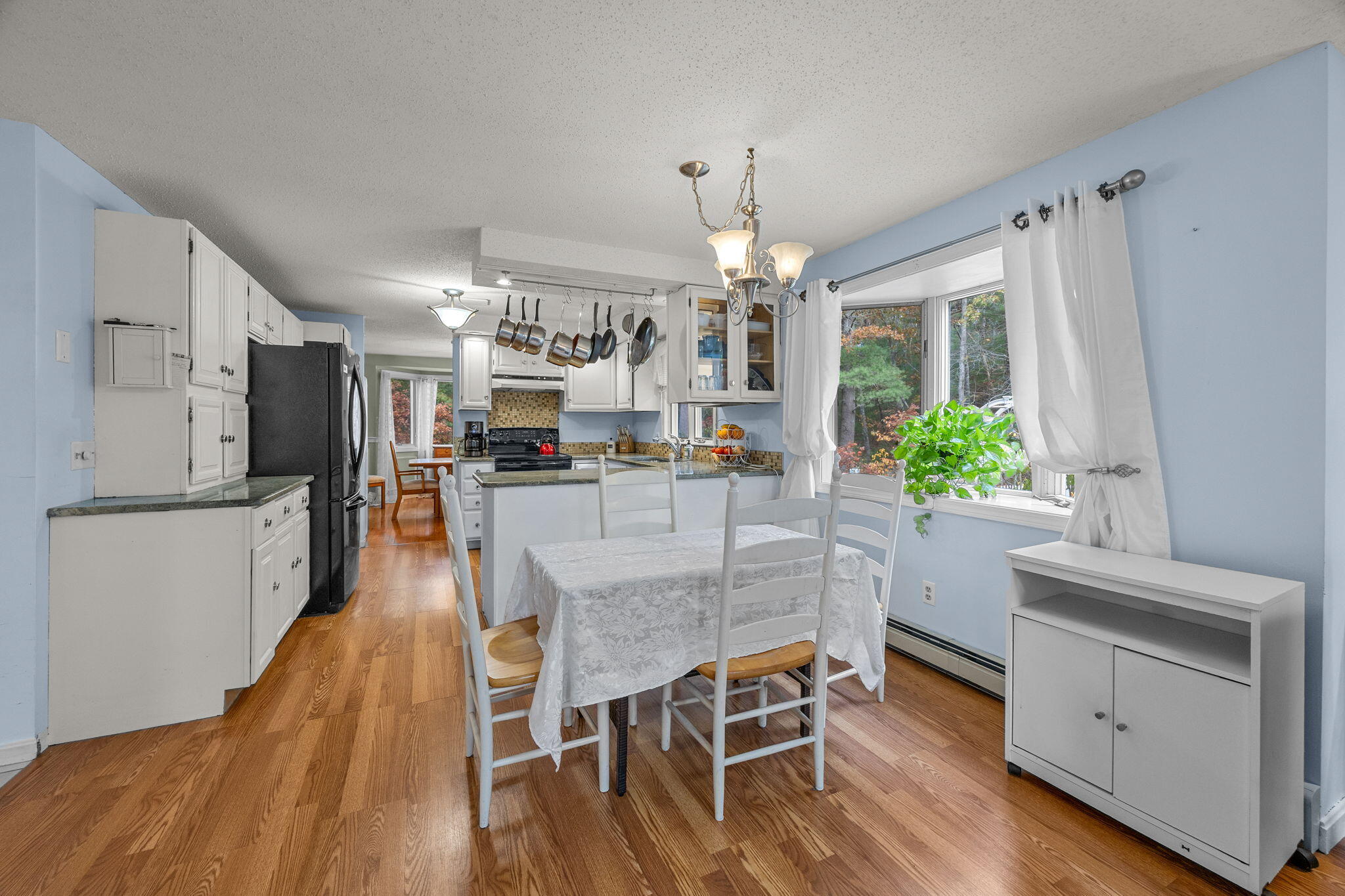 12 Beachwood Road Bourne, MA 02532 - Photo 25 of 64 a dining room with wooden floor a chandelier a wooden table and chairs