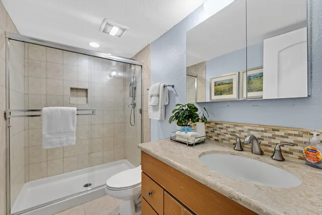 a bathroom with a granite countertop sink a toilet and shower