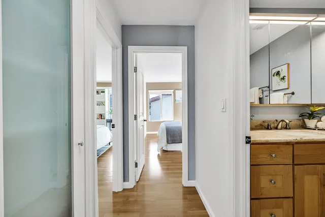 a view of a hallway with bathroom and wooden floor