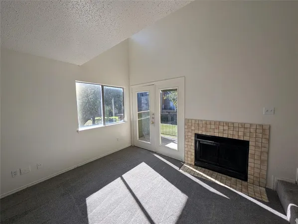 an empty room with windows and fireplace