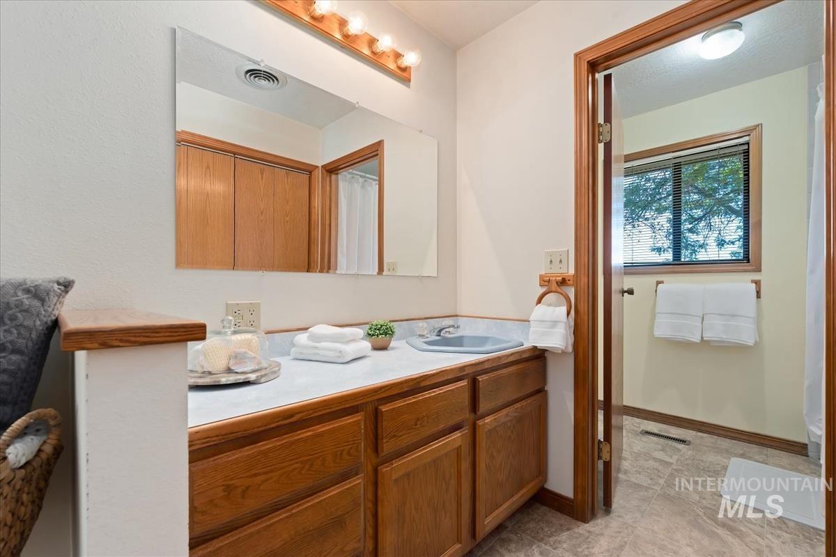 8275 Washoe Road Fruitland, ID 83619 - Photo 17 of 43 Vanity with wood-finish cabinetry, light-toned countertop, and rectangular sink