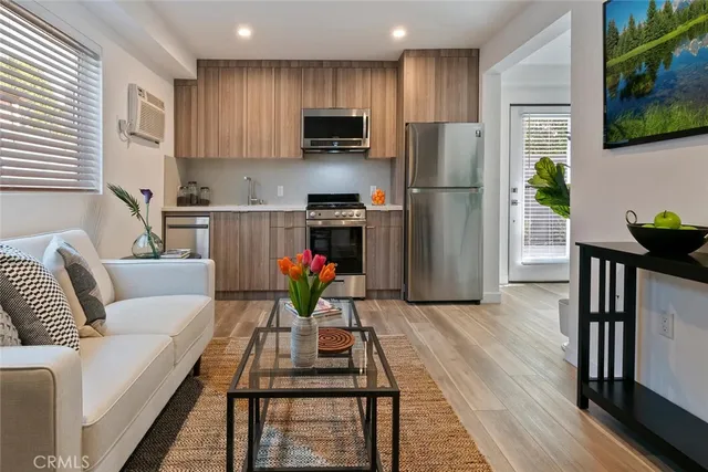 a living room with stainless steel appliances kitchen island furniture and a wooden floor