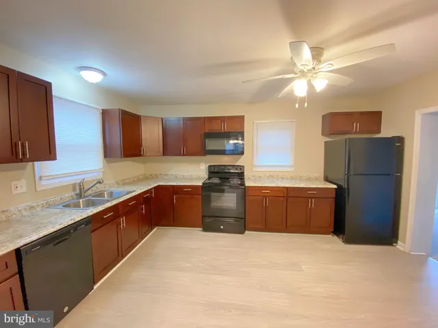 a kitchen with stainless steel appliances granite countertop a refrigerator a sink dishwasher a stove top oven a kitchen island and cabinetry