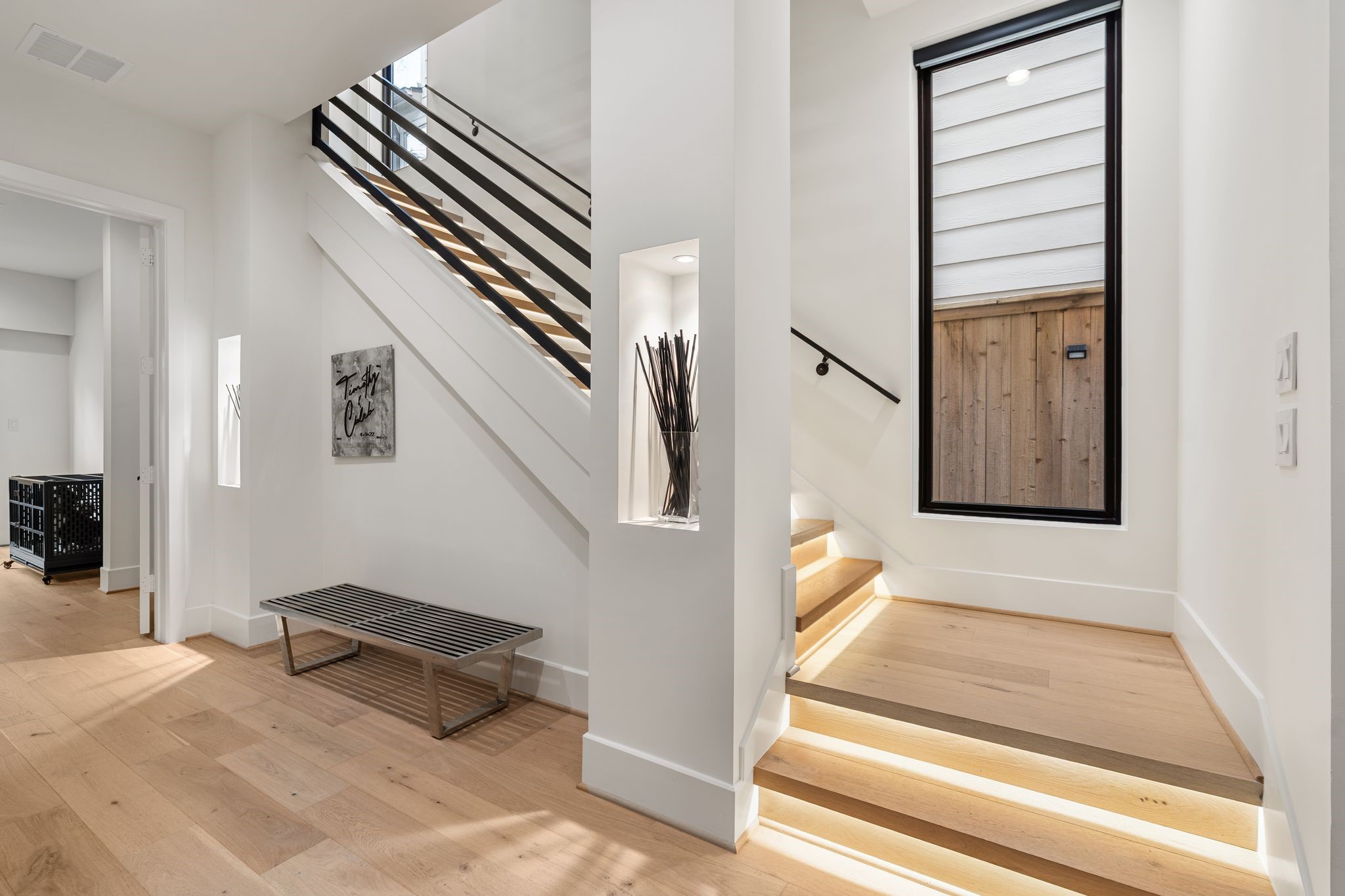 1918 Brun Street Houston, TX 77019 - Photo 11 of 43 A modern staircase with sleek horizontal railing detail leads to the second level of the home, where the main kitchen, dining, and living areas are found. Wide plank wood flooring, abundant natural light, and contemporary architectural features enhance the sense of openness and flow throughout this transition space.