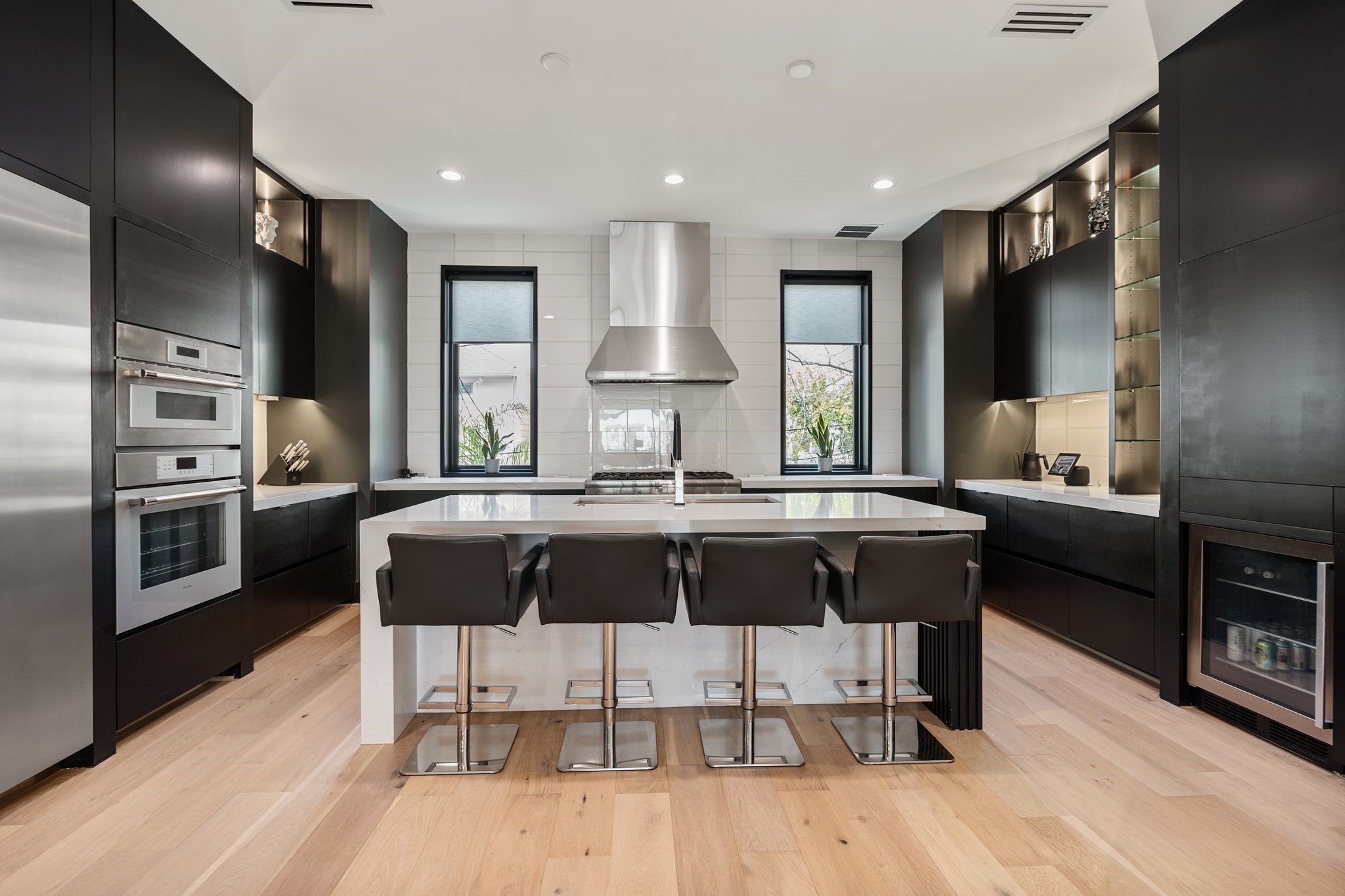 1918 Brun Street Houston, TX 77019 - Photo 12 of 43 The stunning chef’s kitchen is designed to impress, featuring a large waterfall edge island with seating, sleek custom cabinetry, and an eye catching tile backsplash.