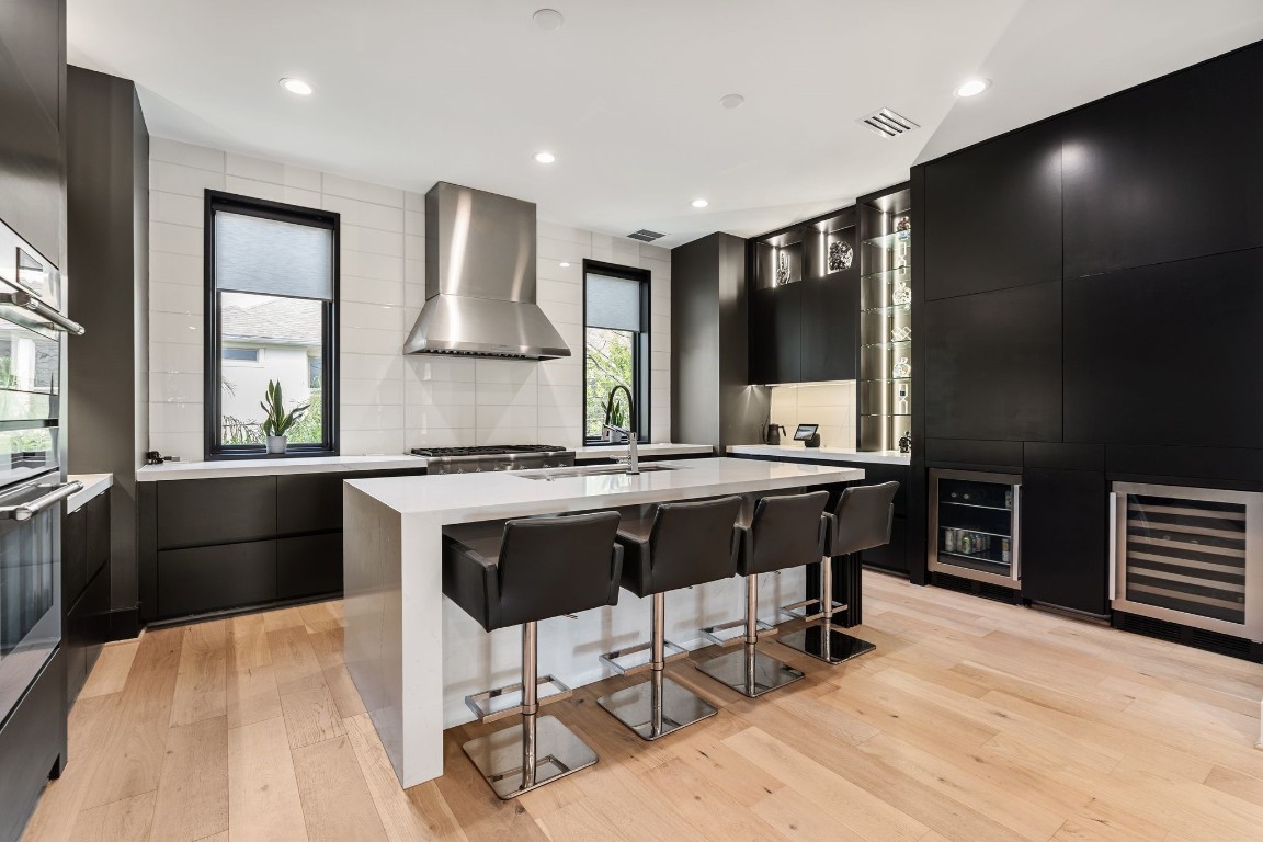 1918 Brun Street Houston, TX 77019 - Photo 14 of 43 Another view of the designer kitchen highlights the expansive waterfall edge island with bar seating. Other features include a built in beverage and wine refrigeration, custom glass shelves to display your favorite pieces, and windows that flood the space with natural light.