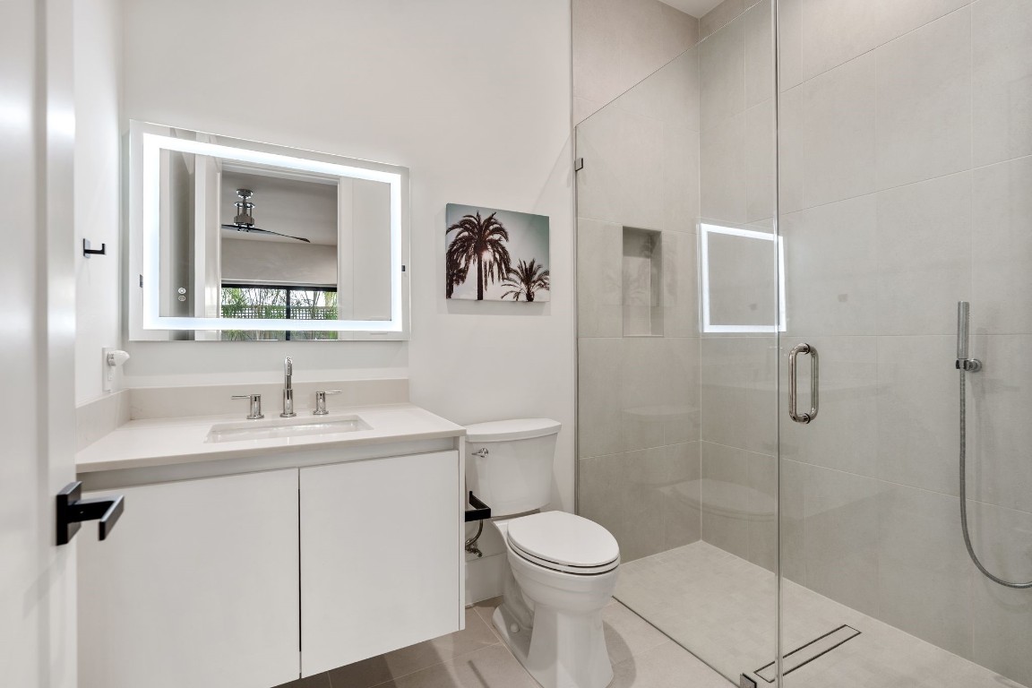 1918 Brun Street Houston, TX 77019 - Photo 10 of 43 The first floor ensuite bathroom showcases a clean, modern design with a sleek floating style vanity, contemporary fixtures, and a backlit mirror. The spacious walk in glass enclosed shower with neutral tile surround and a built in niche creates a spa inspired atmosphere.