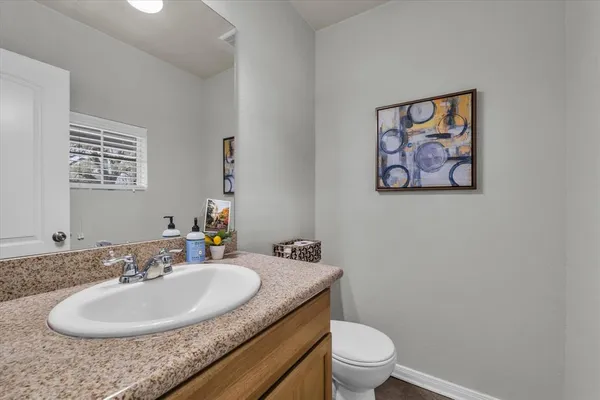 a bathroom with a granite countertop sink a toilet and a mirror