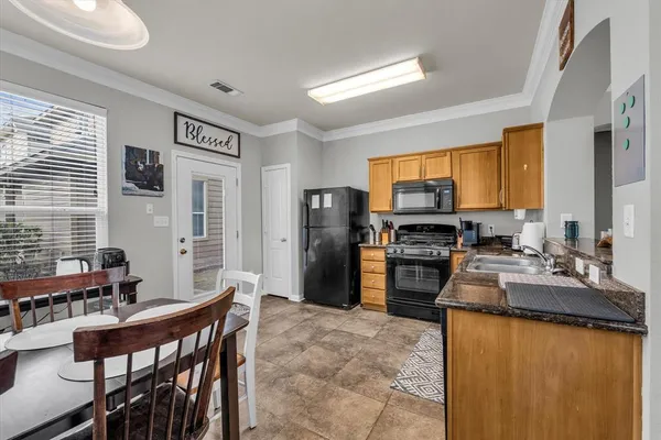a kitchen with stainless steel appliances granite countertop a refrigerator a stove a sink a dining table and chairs with wooden floor