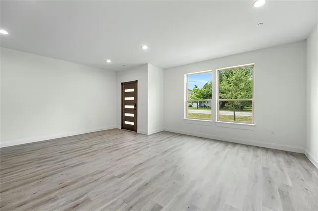 a view of an empty room with wooden floor and a window