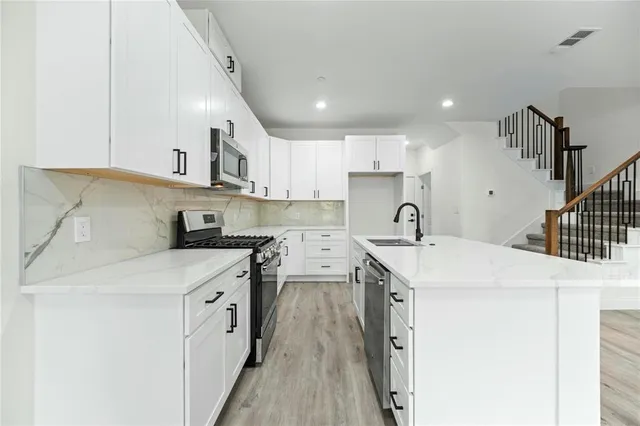 a kitchen with stainless steel appliances granite countertop a sink a stove and a refrigerator
