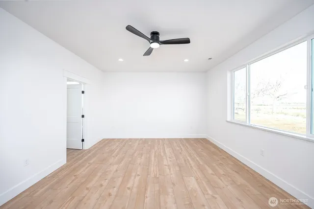a view of empty room with wooden floor and fan