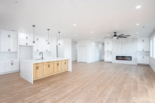 a large kitchen with stainless steel appliances kitchen island granite countertop a stove a sink and white cabinets