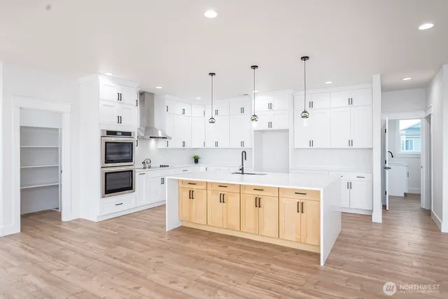 a large kitchen with stainless steel appliances kitchen island granite countertop a large counter top and a stove top oven