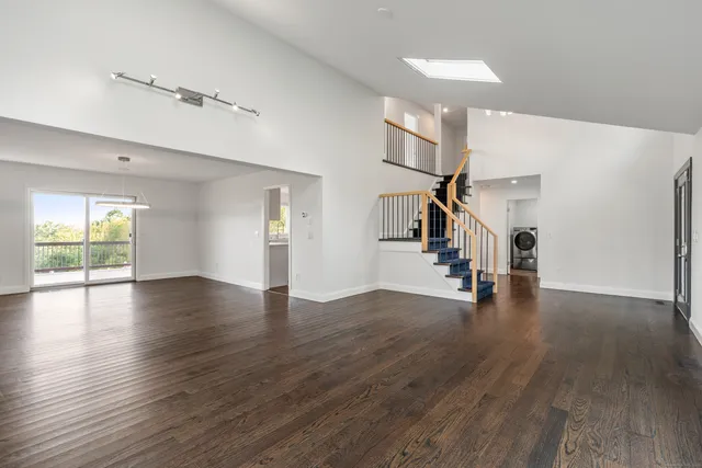 a hallway with wooden floor staircase and a living room