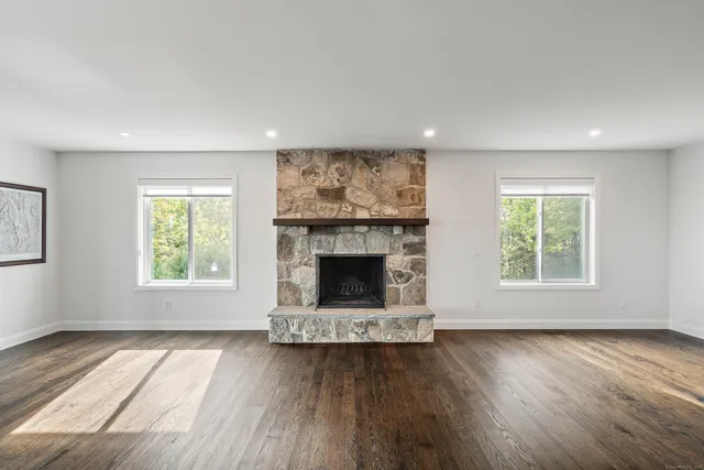 a view of empty room with wooden floor and fireplace