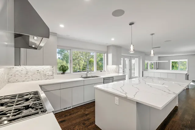 a kitchen with stainless steel appliances granite countertop a stove a sink and a large window
