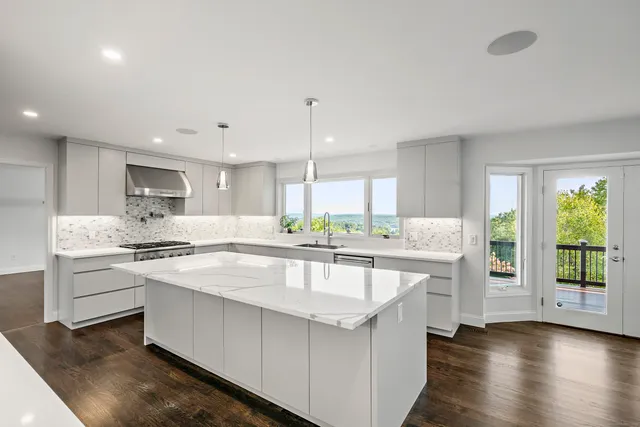 a large white kitchen with lots of counter space wooden floor and appliances