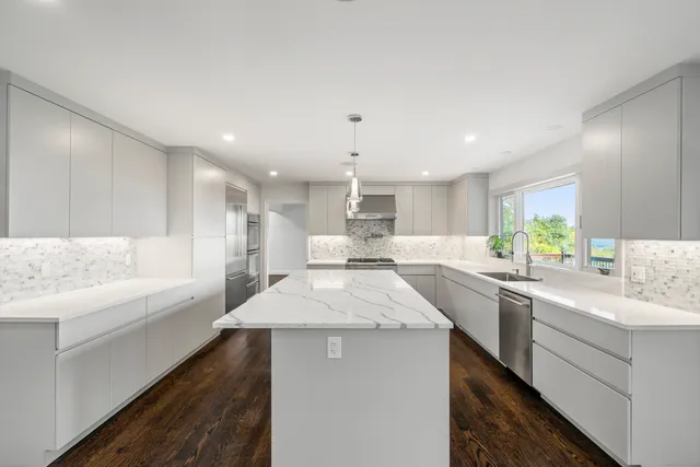 a large white kitchen with wooden floors and white walls