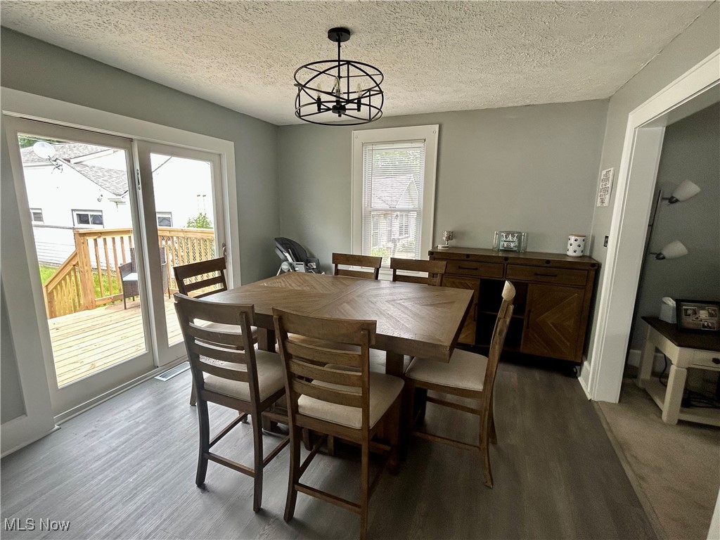 935 Lilly Road Alliance, OH 44601 - Photo 12 of 31 Dining space with dark wood-style floors, a chandelier, and a textured ceiling