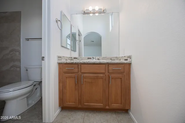 a bathroom with a granite countertop sink mirror vanity and toilet