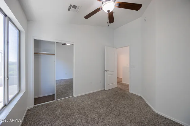 an empty room with closet and a chandelier fan