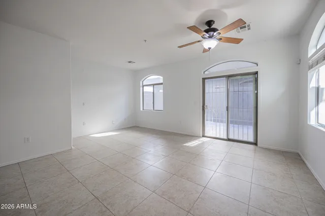 a view of an empty room with a chandelier fan and windows