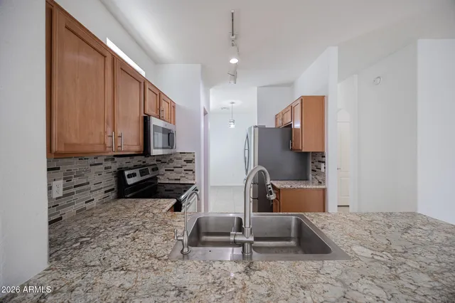 a kitchen with stainless steel appliances granite countertop a stove a sink and a refrigerator