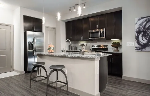 a kitchen with stainless steel appliances granite countertop a stove top oven a sink and a refrigerator