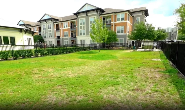 a view of a big house with a big yard plants and large trees