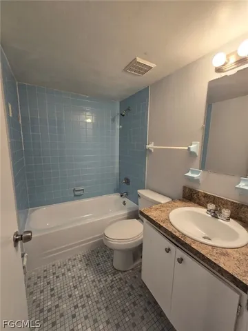 a bathroom with a granite countertop sink a toilet a mirror and bathtub