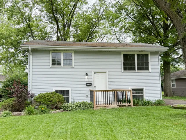 a view of a house with a yard and a large tree